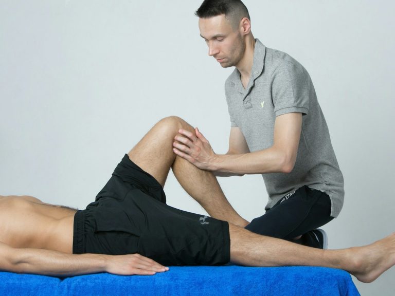 Fisios a domicilio en Madrid Fisioterapeuta realizando un tratamiento a domicilio en la pierna de un paciente.