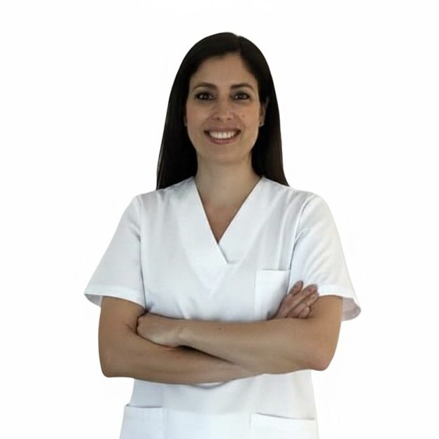 Teresa Leo Jiménez Fisioterapeuta a domicilio Fisioterapeuta a domicilio con bata blanca sonriente, brazos cruzados y fondo blanco.