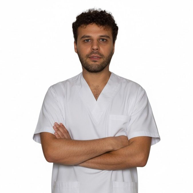 Simone Longo Fisioterapeuta a domicilio Fisioterapeuta con bata médica cruzando los brazos, fondo blanco.