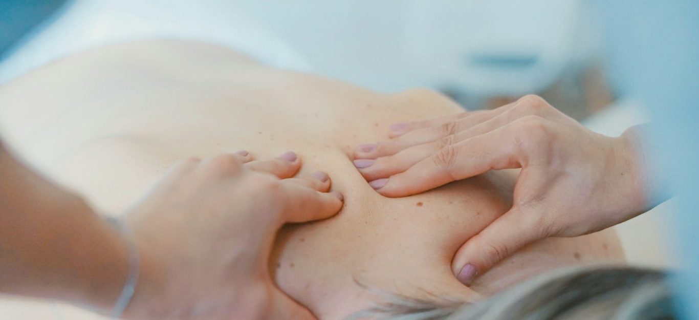 Fisioterapia a domicilio barrio de aravaca Manos realizando un masaje en la espalda de una persona tumbada.